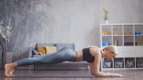 Young and sporty girl in sportswear is doing exercises in home interior.