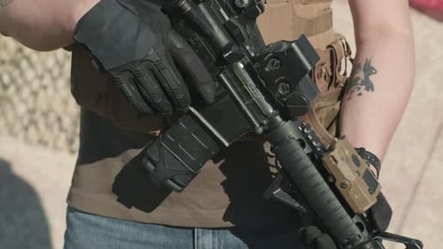 Man Holds Rifle with American Flag Background