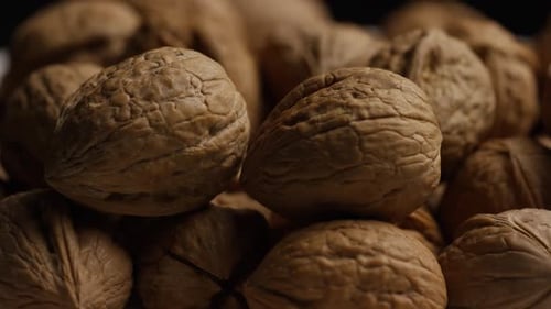 Cinematic, rotating shot of walnuts in their shells on a white surface - WALNUTS