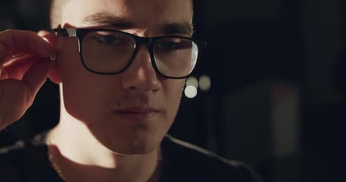 Close View of Man in Glasses Wears Wireless Headphones on Ears Indoors