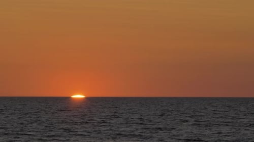 Romantic sunset over the calm Baltic sea, big red Sun sets over the horizon in summer, medium shot f