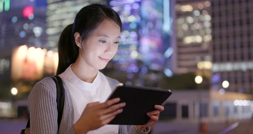 Business Woman Reading on Tablet Computer in City at Night