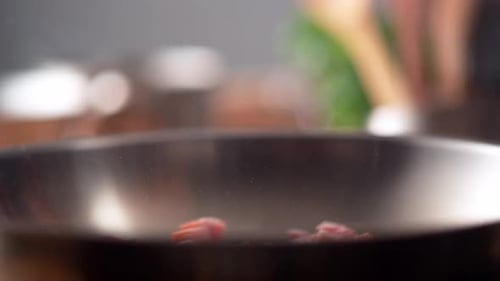 Camera follows cooking bacon in a pan. Slow Motion.