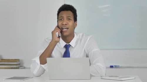 Young Man Talking on Phone at Office Desk