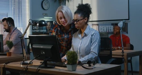Woman Instructing Coworker at a Support Center