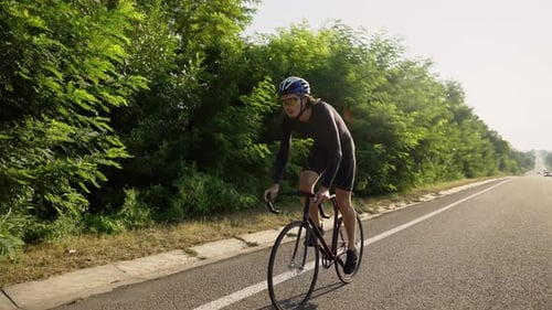 Professioneller männlicher Radfahrer mit Helm fährt Fahrrad auf einer leeren Strecke