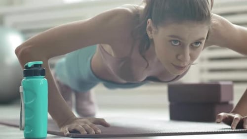 Woman Doing Pushups on Mat in Bright Room