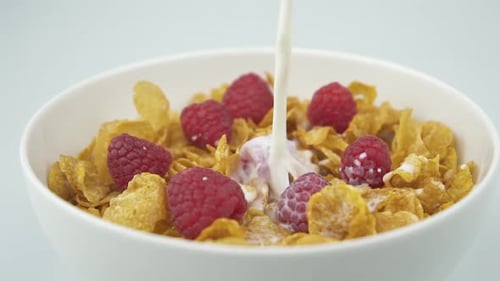Milk Pouring into Bowl of Cereal and Raspberries