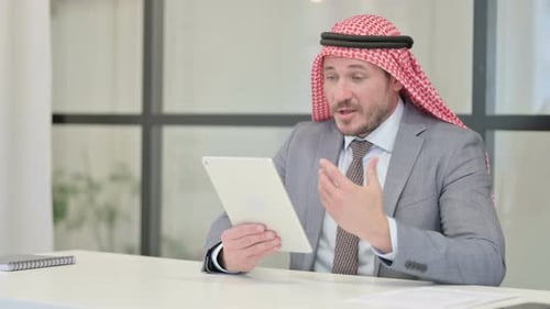 Middle Aged Arab Businessman making Video Call on Tablet in Office