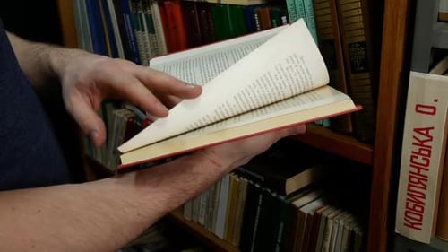 Hands Reading Pages of a Red Book