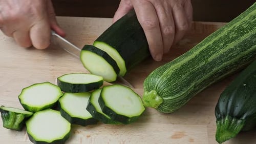 Person Slicing Fresh Zucchini on Cutting Board