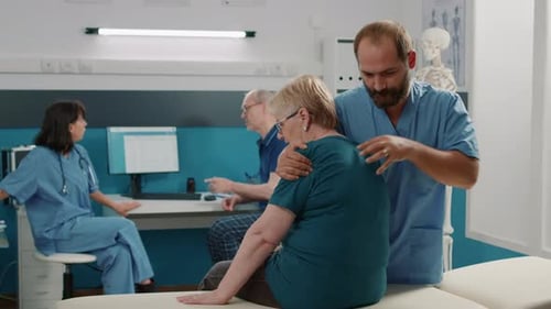 Physical Therapist Massaging Senior Woman's Shoulder in Office