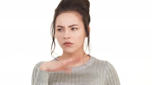 Young Caucasian Girl with Brunette Hair Standing on White Background and Smelling Something Bad in