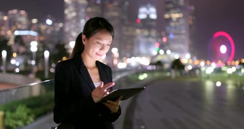 Woman Uses Tablet in City at Night