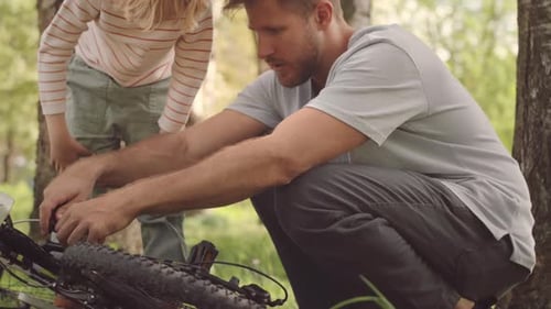 Man Repairing Bicycle with Child in Forest