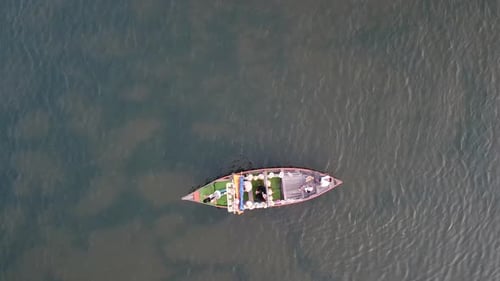 Vue aérienne d'un petit bateau touristique naviguant sur la rivière de la ville de Hoi An en journée.