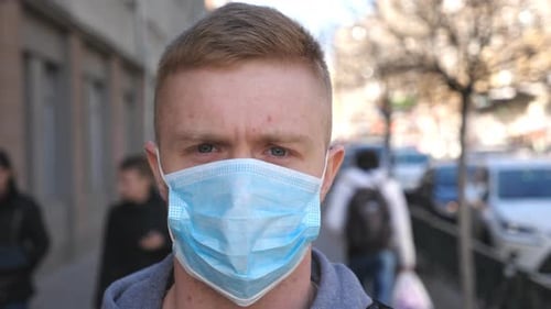 Portrait of Young Man with Medical Face Mask Stands at City Street. Guy Wearing Protective Mask From