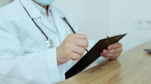 Man Doctor in Hospital Talking to a Patient and Taking Notes Closeup