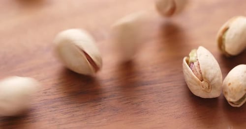 Pistachios Falling onto a Wooden Surface