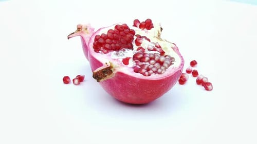 Halved Pomegranate Fruit with Seeds on White Surface