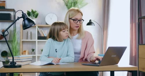 Woman Helping Girl with Schoolwork at Home