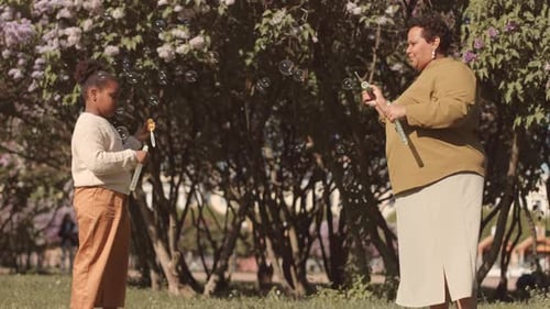 Mom and Daughter Blowing Soap Bubbles in Park