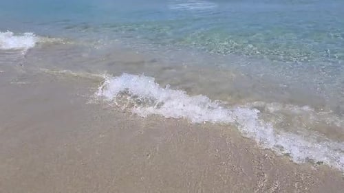 Close up of waves break on tropical yellow sand beach