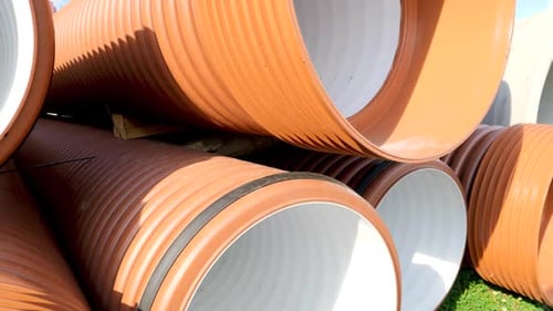 Closeup Dolly Shot of New Plastic Pipes and Tubes Stacked on the Building Site