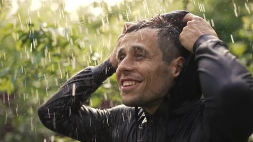 Fröhlicher junger Mann unter Regen