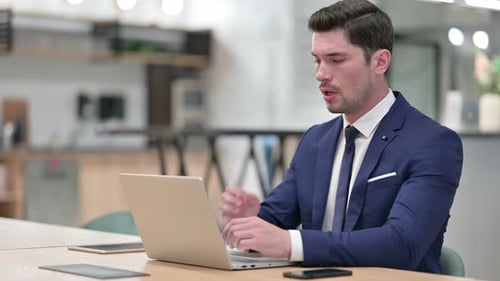 Sick Businessman with Laptop Coughing in Office
