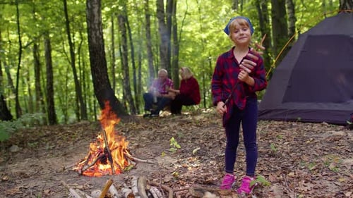 Girl Roasting Sausages at Campfire in Forest