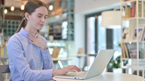 Young Woman Coughing While Working on Laptop