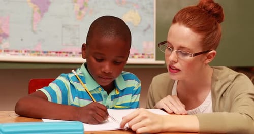 Dedicated Teacher Helping Young Student in Classroom