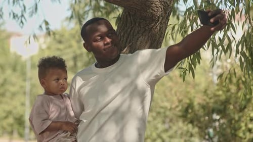Father and Child Take Selfie in Park