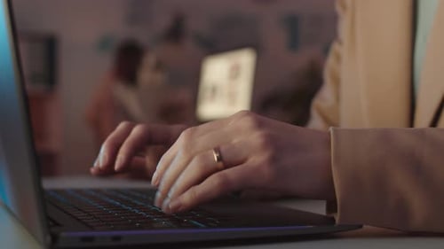 Weibliche Hände tippen nachts im Büro auf Laptop