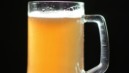 Aufführung von wunderschönem frischen Bier mit Seifenblasen und Schaum in einem Glasbecher mit Wassertropfen