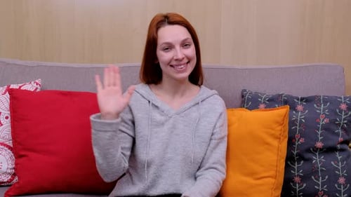Friendly Woman Waving Hello on Couch