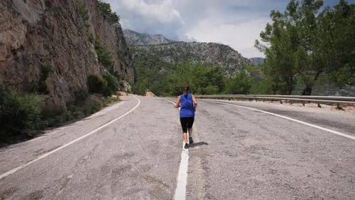 Energetic woman running on mountain road.