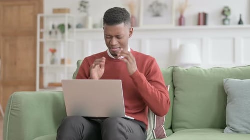 Man Experiencing Discomfort Using Laptop on Sofa
