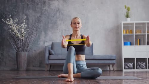 Blonde Woman Exercising with Resistance Band at Home
