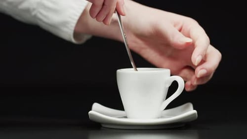 Hand Stirring Coffee in White Cup