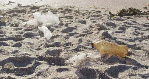 Close up of plastic bottle and rubbish lying on empty dirty beach