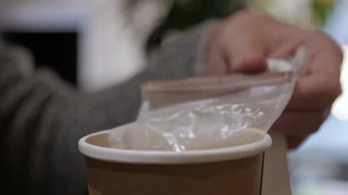 Hands Open a Cup of Tea and Pick Up a Bag of Tea