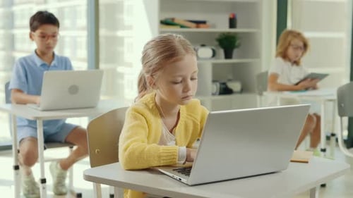 School Girl Using the Computer Sitting in the Class During Computer Science Lesson and Other Pupils