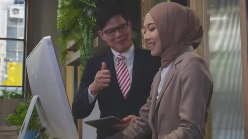 Entrepreneur talking with employee and looking desktop computer together at office.