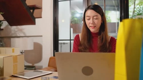 Woman Uses Laptop With Shopping Bags at Desk