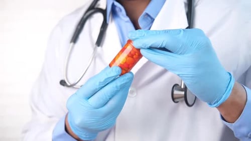 Doctor Hand in Protective Glass Holding Pill Container