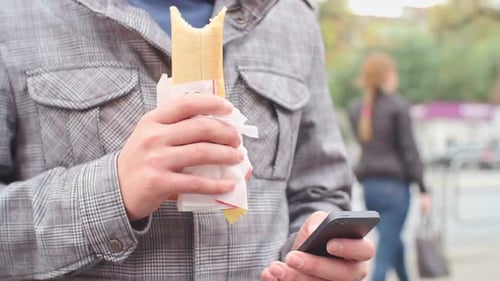Man Using Phone While Eating Sandwich
