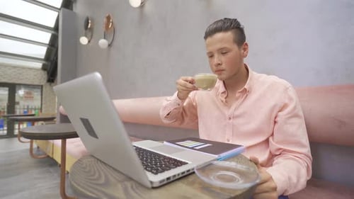 Young Adult Working on Laptop in Cafe
