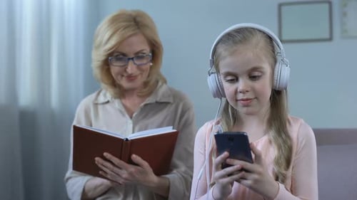 Girl in Headphones Listening to Music and Grandma Reading Book, Generation Gap